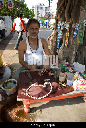 Eine Straße Verkäufer verkaufen Betel Blätter unter dem Schatten eines am Straßenrand Baumes Varanasi, Indien. Stockfoto