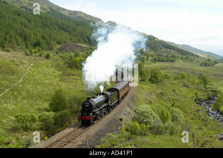 Dampfzug fährt bergauf über Glenfinnan Station in Richtung Mallaig an einem sonnigen Sommertag Stockfoto