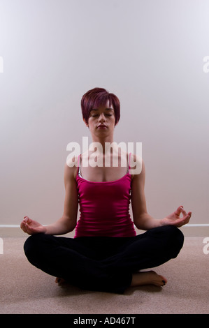 Junge Frau praktizieren Yoga drinnen Augen geschlossen Stockfoto