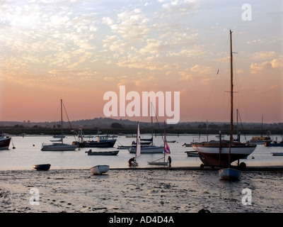 West Mersea Sunset und Boote an Anlegestellen bei Ebbe auf dem Strood Channel in der Nähe der Flussmündung des Flusses Blackwater Mersea Essex England Stockfoto