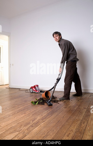 Ein Mann, der Boden aus eine verschüttete Topfpflanze aufsaugen Stockfoto