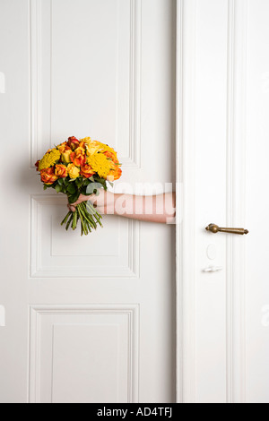 Ein Mann hält einen Blumenstrauß in eine Tür Stockfoto