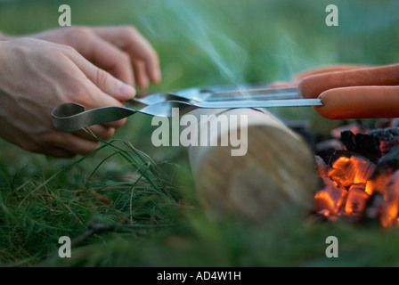 Detail eines Mannes grillen Würstchen über dem Feuer Stockfoto