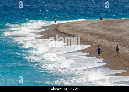 Horizontale Luftaufnahme von Touristen zu Fuß entlang einer leeren Strand in der frühen Abendsonne mit Wellen, in. Stockfoto