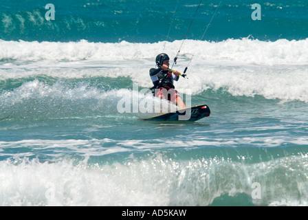 Horizontale Nahaufnahme von kaukasischen männlichen Kitesurfer in eine schiefe Stellung durch die Schaffung eines Bogens von Spray Wellen surfen Stockfoto