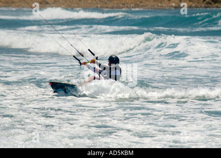 Horizontale Nahaufnahme von kaukasischen männlichen Kitesurfer in einer hockenden Position krachend durch die Wellen Stockfoto