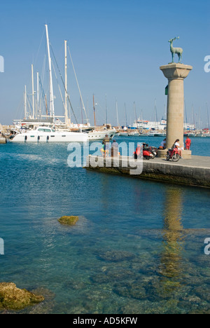 Vertikale Ansicht der Hirsch Reh-Statue am Eingang des Mandraki-Hafen spiegelt sich im Wasser an einem sonnigen Tag. Stockfoto