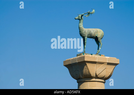 Horizontale Nahaufnahme der Hirsch Reh Statue auf einer hohen Säule am Eingang des Mandraki Hafen gegen ein strahlend blauer Himmel Stockfoto