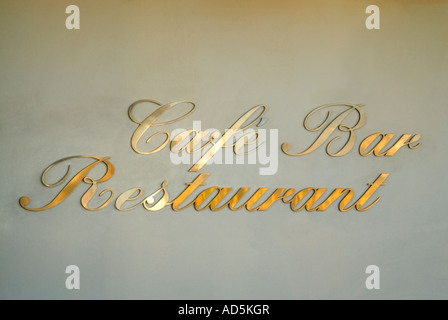 Horizontal in der Nähe von Cafe, ein Restaurant und eine Bar anmelden im klassischen swirly gold Schrift auf einem cremefarbenen Wand. Stockfoto