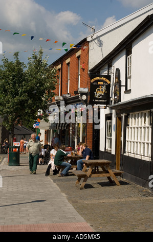 Menschen trinken vor Pub in der Sonne auf der großen Straße Llanidloes Powys Wales UK Stockfoto