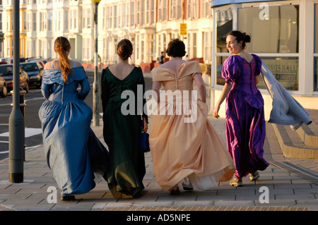 Vier Frauen in Seide ball Kleider zu Fuß entlang der Promenade Aberystwyth Ceredigion West Wales - gesehen von hinten, UK Stockfoto