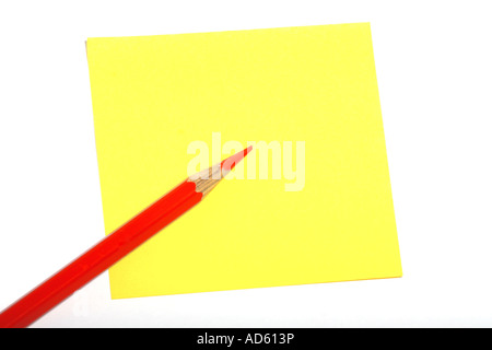 Ein roter Bleistift, der diagonal auf einer gelben Haftnotiz vor weißem Hintergrund platziert wird, schafft eine helle und minimale Komposition. Stockfoto