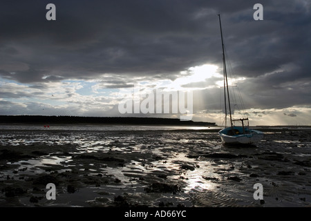 Boot auf der Findhorn Flussmündung Wattenmeer in Findhorn Bay bei Ebbe mit einem stürmischen dunkel bewölkter Himmelshintergrund. Moray, Schottland Stockfoto