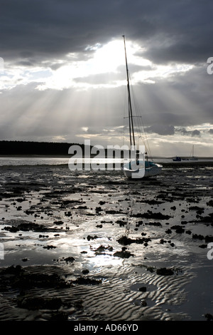 Boot auf der Findhorn Flussmündung Wattenmeer in Findhorn Bay bei Ebbe mit einem stürmischen dunkel bewölkter Himmelshintergrund. Moray, Schottland Stockfoto