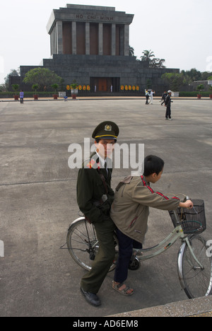 Vietnam Hanoi Hoan Kiem District Ho Chi Min Mausoleum Soldaten und Kind reitet auf einem Fahrrad infront von Denkmal Stockfoto