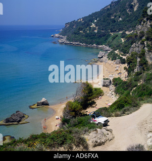 Blick auf schiere Baum bedeckt Klippen staubige Straße und Jeep zum Sandstrand mit Felsen Mirtiotissa Beach Korfu griechische Inseln Stockfoto