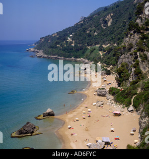 Luftbild mit Blick auf schiere Baum bedeckt Klippen bis hin zu sandigen Strand und Felsen unterhalb Mirtiotissa Beach Korfu griechische Inseln Stockfoto
