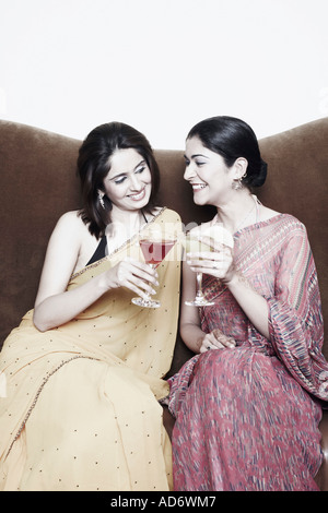 Zwei junge Frauen sitzen auf einer Couch Toasten mit Martini-Gläser Stockfoto