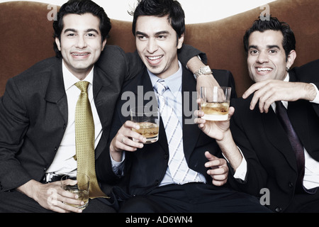 Nahaufnahme von drei jungen Männern hält Gläser Whiskey Stockfoto