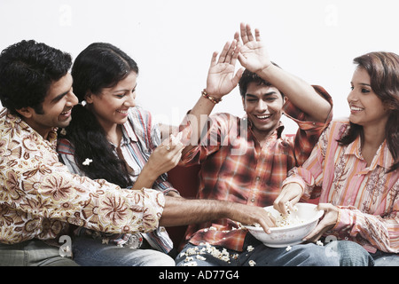 Nahaufnahme von zwei junge Paare sitzen zusammen auf einer Couch Essen popcorn Stockfoto