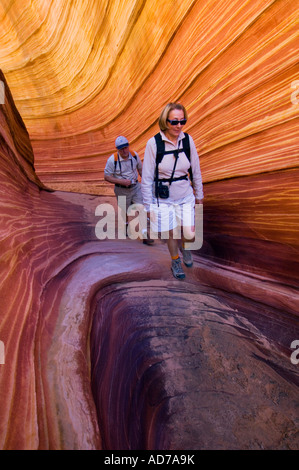 Touristen-paar Wandern durch Sandstein-Formationen an The Wave Coyote Buttes Paria Canyon Vermilion Cliffs Wilderness Arizona Stockfoto