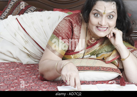 Porträt einer reifen Frau ballte ihre Zähne auf dem Bett liegend Stockfoto