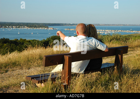 Paar auf Bank genießen Sie den Blick über Christchurch Harbour vom Hengistbury Kopf Dorset England UK Stockfoto