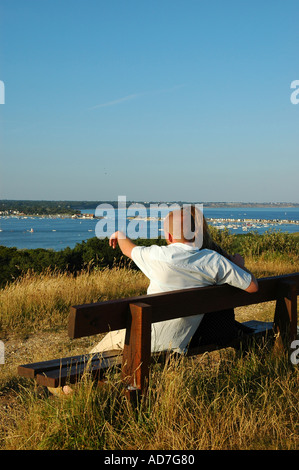 Paar auf Bank genießen Sie den Blick über Christchurch Harbour vom Hengistbury Kopf Dorset England UK Stockfoto