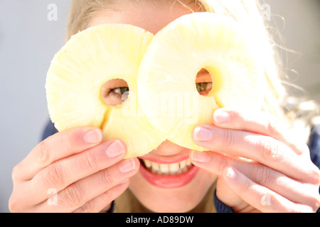 Porträt der jungen Frau mit Ananasscheiben vor Augen, Lächeln Stockfoto