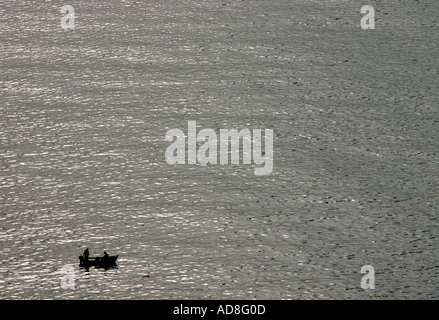 Zwei Fischer arbeiten in einem Boot gegen eine graue Gold glitzerte ruhigen See, der scheint, in die Unendlichkeit in der Nähe von Salobrena dehnen Stockfoto