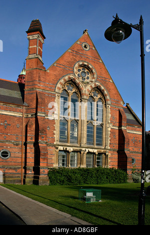 Die Halle an der Queens University bei Sonnenuntergang mit dem orangenen Backstein leuchtet hell vor einem dunklen blau und wolkenlosen Himmel Stockfoto