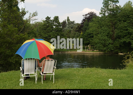 Touristen übernachten unter einem bunten Regenschirm am Ufer der Themse bei Runnymede. In Der Nähe Von Windsor Surrey. England 2006 2000er Jahre UK HOMER SYKES Stockfoto