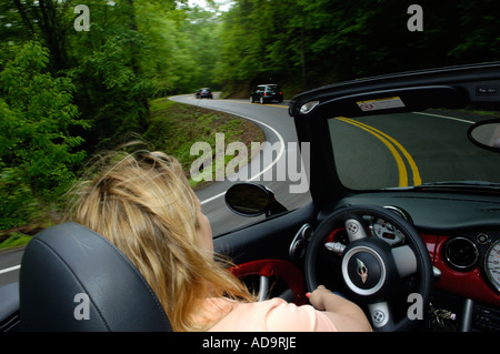 Autofahrerin einen MINI Cooper S Cabrio auf einer kurvenreichen Straße mit mehr MINIs voraus Stockfoto