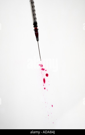 Rotes Blut vergossen aus Spritze auf weißem Hintergrund Stockfoto