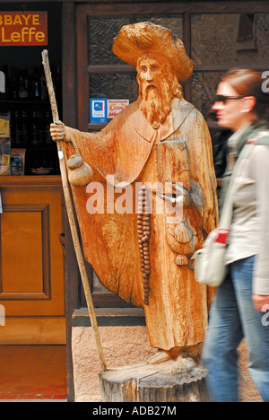 Frau vorbei an Holzskulptur von St. James, Conques, Midi-Pyrenäen, Frankreich Stockfoto