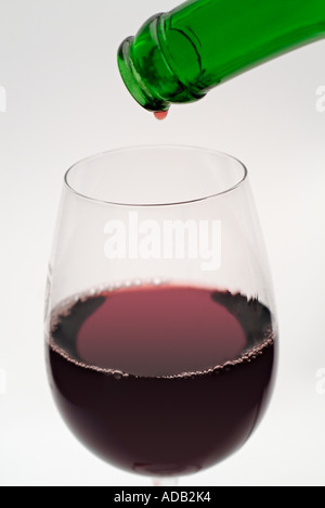 Nahaufnahme von den letzten Tropfen Rotwein aus der Flasche in ein Glas Wein in Strömen Stockfoto