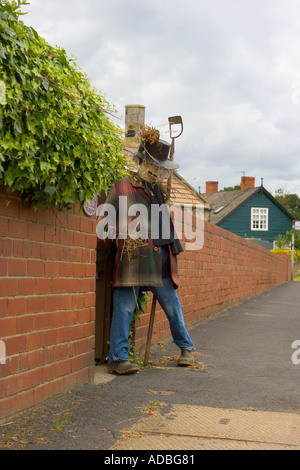 Gärtner Vogelscheuche holding Hoe. 'Bus Stop' im Sommer Hinderwell Sommer Gala. Warten auf Transport, Spendenaktion im Dorf. Stockfoto