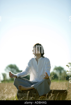 Junger Mann beim Yoga im Feld Stockfoto