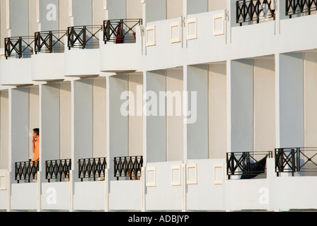 Horizontale abstrakt Nahaufnahme eines einsamen Mannes stehend auf seinem Hotelbalkon mit einer ruhigen Zigarette in der Abendsonne. Stockfoto