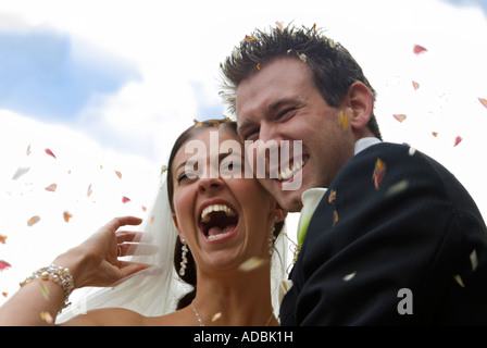 Horizontale Porträt der glückliche Braut und Bräutigam bei ihrer Hochzeit traditionell mit Konfetti geworfen über sie als Glücksbringer. Stockfoto