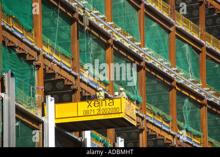 Grüne Sicherheitsnetz Stahlrahmen Büro bau Baustelle errichtet wird, kein Gerüst Menschen arbeiten auf Auskragenden Arbeitsbühne London UK Stockfoto