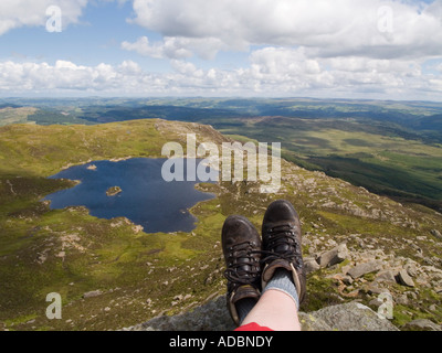 Paar Füße tragen Stiefel im Vordergrund mit Blick hinunter auf Llyn y Foel von Moel Siabod Daear Ddu Ostgrat in Snowdonia-Nationalpark-Wales Stockfoto