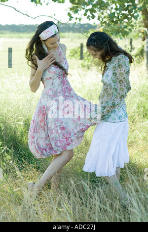 Zwei junge Frauen im Feld stehen, Blick einen auf das andere Kleid Stockfoto