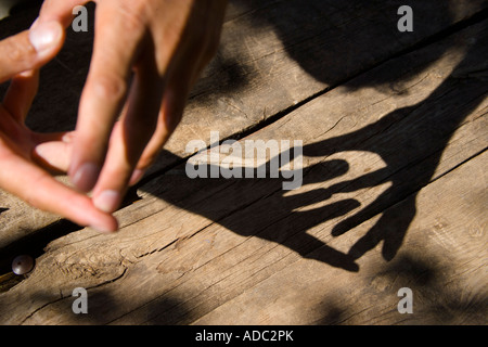Männliche Hände werfen Schatten auf Holztisch Stockfoto