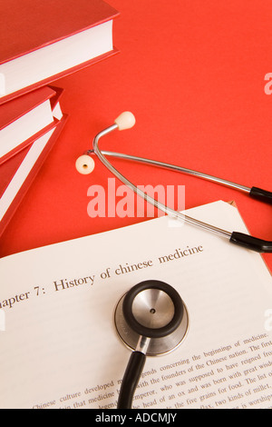 Nachschlagewerke auf der chinesischen Medizin mit einem Stethoskop auf einem roten Hintergrund isoliert Stockfoto