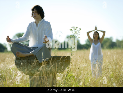 Junge Männchen und Weibchen beim Yoga im Feld Stockfoto