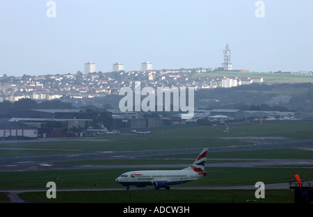 British Airways Flugzeug wartet darauf, von Aberdeen Airport am Abend mit der Stadt im Hintergrund abheben Stockfoto