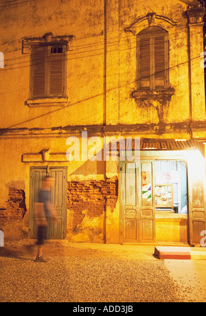 Mann zu Fuß vorbei an bröckelt kolonialen Gebäude in der Nacht Stockfoto