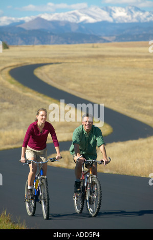 Applying paar Fahrrad fahren auf einem Pfad mit Bergkette im Hintergrund Stockfoto