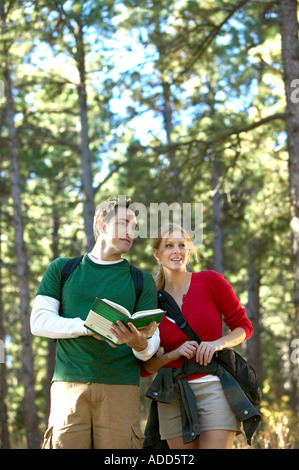 Caucasian Paar konsultieren Ratgeber beim Wandern durch Kiefern am Lehrpfad Stockfoto